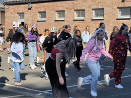 Leerlingen dansen op de speelplaats